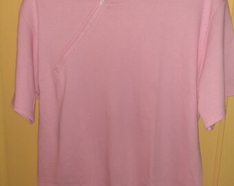 May include: A pink short-sleeved t-shirt with a diagonal zipper on the front. The shirt has a crew neck and is made by Port & Company.