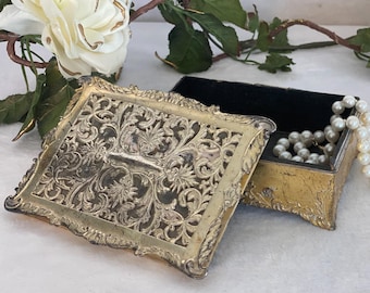 May include: A gold filigree jewelry box with a black velvet interior. The box is open and a pearl necklace is inside.