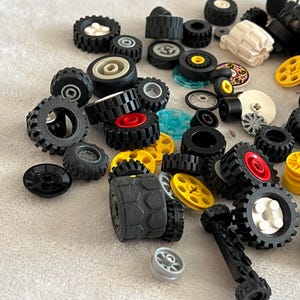 K&ouml;nnte beinhalten: Eine Sammlung verschiedener Spielzeugautor&auml;der in unterschiedlichen Gr&ouml;&szlig;en und Designs. Die R&auml;der sind haupts&auml;chlich schwarz mit Akzenten in Rot, Gelb, Wei&szlig; und Silber. Einige R&auml;der haben strukturierte Reifenprofile.