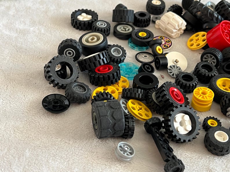 K&ouml;nnte beinhalten: Eine Sammlung verschiedener Spielzeugautor&auml;der in unterschiedlichen Gr&ouml;&szlig;en und Designs. Die R&auml;der sind haupts&auml;chlich schwarz mit Akzenten in Rot, Gelb, Wei&szlig; und Silber. Einige R&auml;der haben strukturierte Reifenprofile.