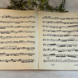 May include: Open vintage sheet music book with two pages of musical notation. The pages are aged with a cream color, and the musical notes are printed in black ink. The text "Adagio" and "Finale" are visible.