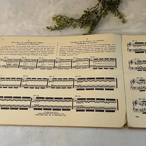 May include: Open book of sheet music with musical notes and text. The pages are aged with a yellowed tone. The text includes the title "Exercises for rendering the fingers independent of each other". The book is open to several pages of musical notation.