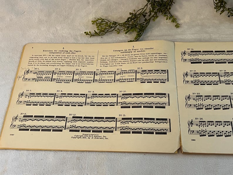 May include: Open book of sheet music with musical notes and text. The pages are aged with a yellowed tone. The text includes the title "Exercises for rendering the fingers independent of each other". The book is open to several pages of musical notation.