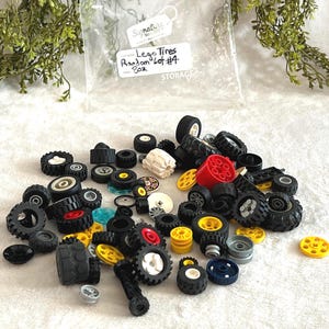 K&ouml;nnte beinhalten: Eine Sammlung verschiedener Lego-Reifen in verschiedenen Gr&ouml;&szlig;en und Farben, darunter Schwarz, Wei&szlig;, Rot und Gelb. Das Bild enth&auml;lt einen transparenten Plastikbeutel mit der Aufschrift "Lego Tires Random Lot #4 8oz."