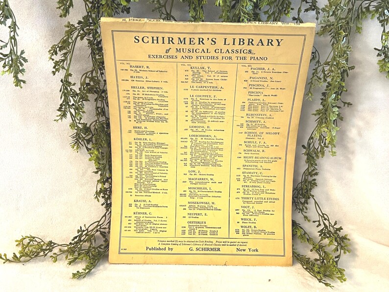 May include: A vintage sheet music book titled "Schirmer's Library of Musical Classics" with exercises and studies for the piano. The cover is yellowed with age and features a list of musical compositions and composers.
