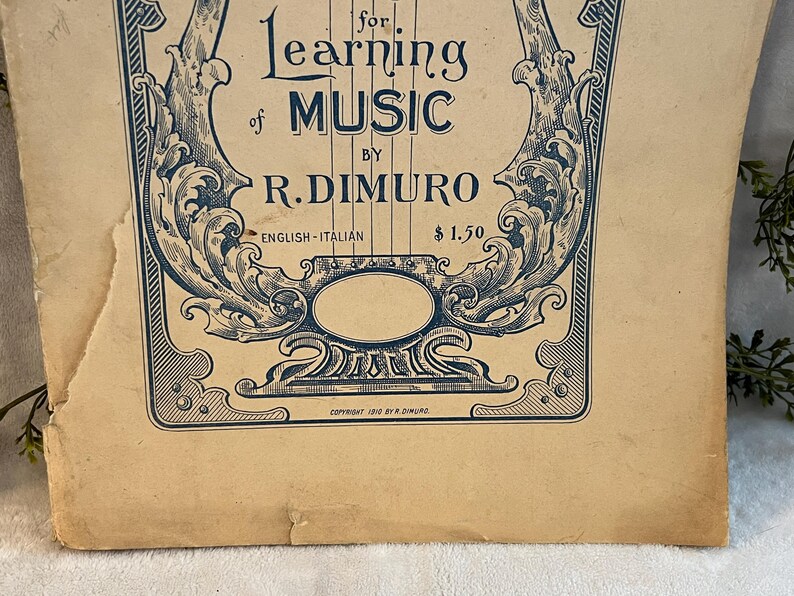 May include: Vintage sheet music cover with ornate blue and white design. The title reads "for Learning of Music" by R. DiMuro. The cover is aged with visible wear and tear, adding to its antique charm. The text "English-Italian" is also present.