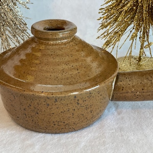 Może przedstawiać: Brązowa ceramiczna naczynie do zapiekania z pokrywką i uchwytem. Naczynie ma kropkowaną glazurę.