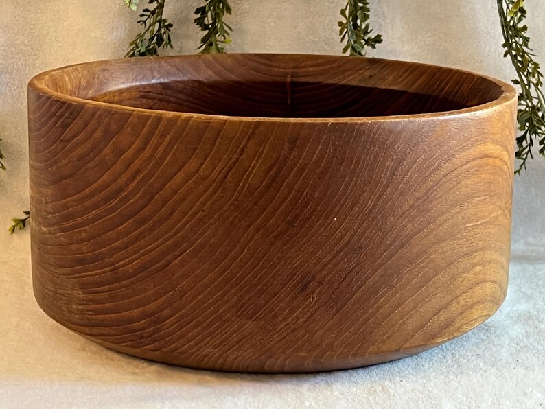 May include: A large, round wooden bowl with a rich, warm brown color. The bowl has a smooth, curved design and visible wood grain patterns. This decorative bowl is suitable for serving or display.