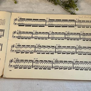 May include: Vintage sheet music with musical notation, featuring numbered sections and handwritten text. The pages are aged with a cream color, and the musical notes are black. The text "Each hand separately" is visible.