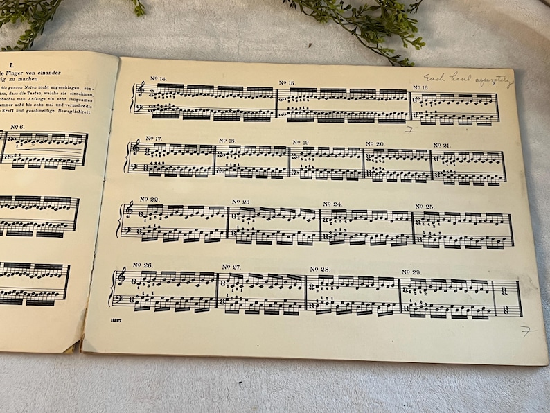 May include: Vintage sheet music with musical notation, featuring numbered sections and handwritten text. The pages are aged with a cream color, and the musical notes are black. The text "Each hand separately" is visible.