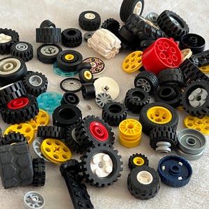 K&ouml;nnte beinhalten: Eine Sammlung verschiedener Spielzeugr&auml;der in Schwarz, Gelb, Rot und Wei&szlig;. Die Auswahl umfasst R&auml;der in verschiedenen Gr&ouml;&szlig;en und Designs sowie andere Bauelemente f&uuml;r Spielzeug.
