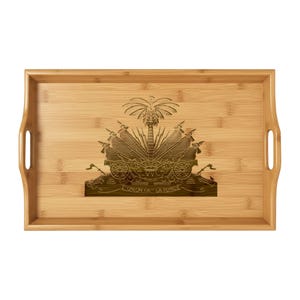 May include: A rectangular bamboo serving tray with integrated handles. The tray features a detailed, dark brown engraving of the Haitian coat of arms in the center. The phrase "L'UNION FAIT LA FORCE" is visible below the emblem.