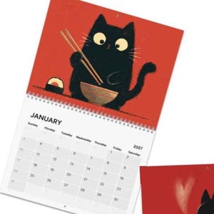 May include: A 2027 wall calendar featuring a black cat illustration on a red background. The cat holds chopsticks over a bowl with a sushi roll nearby. The calendar page shows the month of January with a grid of days and dates.