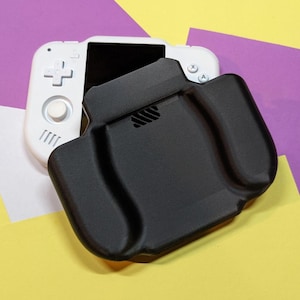 Puede incluir: Una consola de juegos portátil blanca con una funda protectora negra. La consola tiene un mando direccional, botones y una pantalla. La funda negra tiene un diseño contorneado para un agarre cómodo y una ventilación. El fondo es una mezcla de amarillo, morado y blanco.