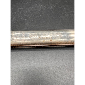 May include: A silver-toned harmonica with the word "PRECIOSA" and "M. HOHNER" engraved on the top. The harmonica has a rectangular shape with multiple holes and a metallic finish. The instrument is likely used for playing music.