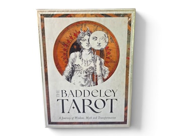 May include: A rectangular tarot deck box featuring an illustration of a figure holding a moon mask. The text reads THE BADDELEY TAROT A Journey of Wisdom, Myth and Transformation. The design includes orange and brown circular sun motifs.