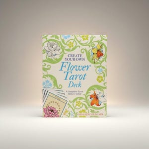 May include: A complete Flower Tarot Deck to color. The box features the text "Create Your Own Flower Tarot Deck" in blue script, with floral illustrations in green, yellow, and orange. A deck of cards is visible on the left side of the box.