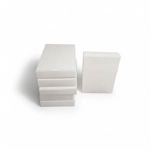 May include: A stack of four rectangular white cardboard boxes positioned vertically, accompanied by a single matching white rectangular box standing upright to the right. Each box features a plain, smooth surface with no visible markings or text.