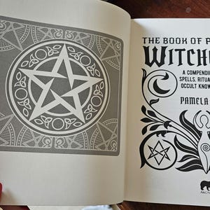 May include: An open book showing a gray and white pentagram design on the left page. The right page displays the title "The Book of Practical Witchcraft" with text: "A compendium of spells, rituals and occult knowledge" by Pamela Ball.