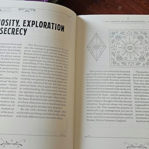 May include: An open book displaying the title "CURIOSITY, EXPLORATION AND SECRECY". The left page has text, the right page has illustrations of geometric shapes and symbols. The book's pages are cream-coloured, with black text.