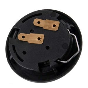 Pu&ograve; includere: Un componente elettrico nero e circolare con due connettori color ottone e una clip metallica argentata. Il componente presenta una serie di piccoli fori ed &egrave; posto su uno sfondo bianco.