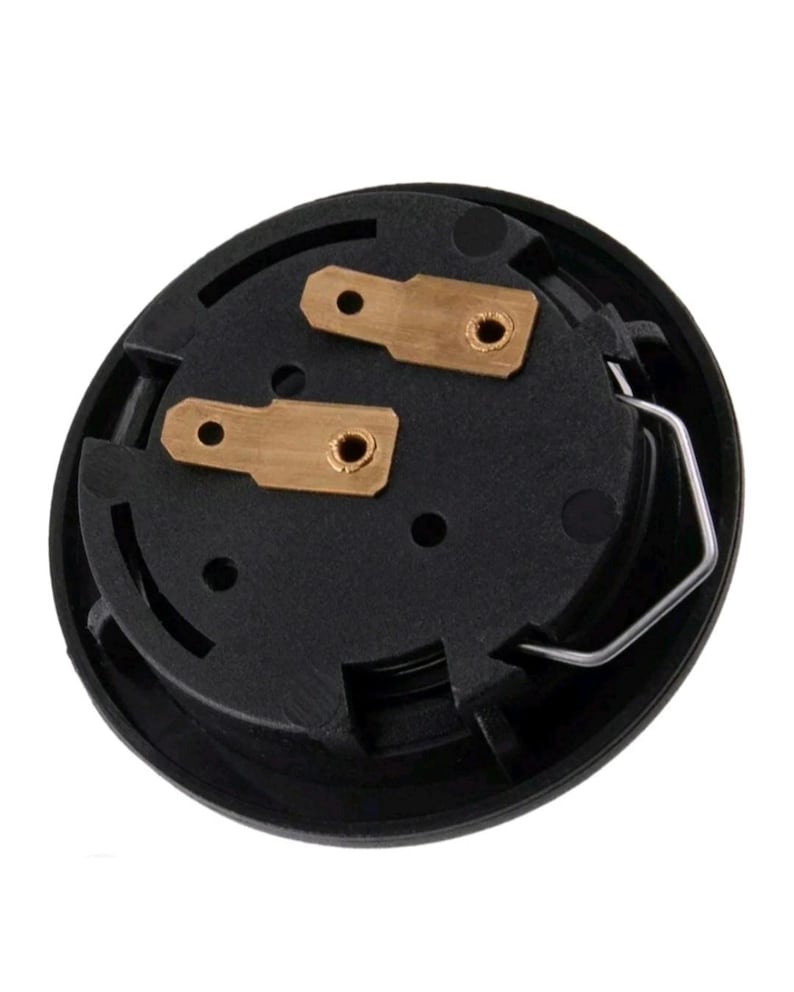 Pu&ograve; includere: Un componente elettrico nero e circolare con due connettori color ottone e una clip metallica argentata. Il componente presenta una serie di piccoli fori ed &egrave; posto su uno sfondo bianco.