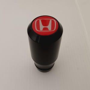 May include: Black gear shift knob with a red and white Honda logo.