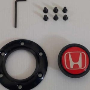 Pu&ograve; includere: Un kit adattatore per mozzo del volante nero con un emblema Honda rosso e bianco, sei viti nere e una chiave a brugola. Il kit include un anello circolare nero con sei fori.