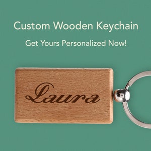 May include: A wooden keychain with the name "Laura" engraved on it. The keychain is attached to a silver metal ring.