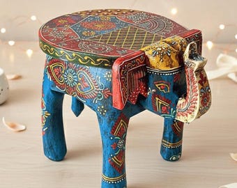 May include: A hand-painted wooden elephant stool. The stool is painted in shades of blue, red, yellow, and gold. The round top features intricate patterns. The elephant's trunk is raised, and the legs are sturdy. A decorative piece for any room.