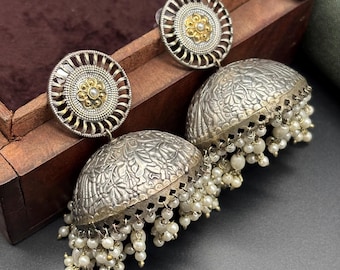 May include: A pair of silver and gold earrings with intricate floral designs and pearl accents. The earrings are round and have a dangling design.