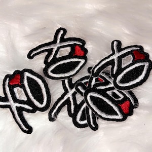 Puede incluir: Cinco parches de hierro bordados en blanco y negro con un diseño de corazón rojo. Los parches presentan un carácter japonés estilizado.