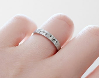 May include: A silver ring with the inscription "jerry & you" engraved on the band. The ring is 3mm wide.