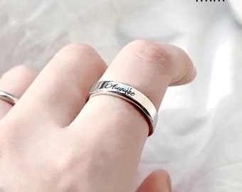 May include: A silver ring with the word "Audie" engraved on it. The ring is 4 mm wide.