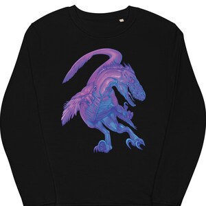 Pode incluir: Camisola de moletom preta com um gráfico de dinossauro roxo e azul. O dinossauro é retratado em uma pose dinâmica com a cabeça virada para o lado e a boca aberta.