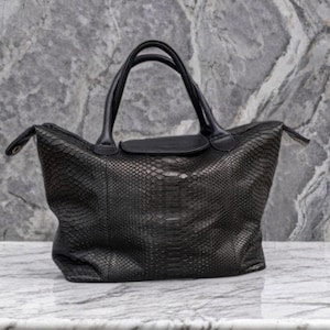 May include: A black leather handbag with a snakeskin pattern. The bag has two top handles and a zipper closure.