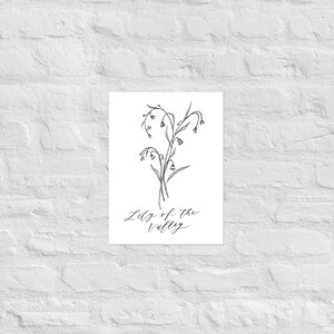 May include: A black and white line drawing of a lily of the valley flower with the text "Lily of the valley" written in cursive below the flower.