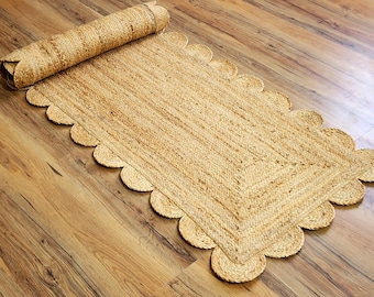 Op de afbeelding: Een vloerkleed van natuurlijke vezels met een gegolfde rand. Het vloerkleed is gemaakt van jute en heeft een lichtbruine kleur.