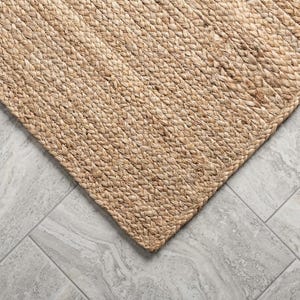 May include: A rectangular area rug crafted from natural tan fibers woven into a thick, braided pattern. The rug features a dense, textured surface with a consistent light brown color throughout, showcasing the intricate interlocking weave design.
