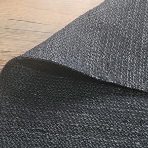 May include: Close-up of a black woven fabric with a textured surface.