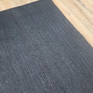 May include: A dark gray woven rug with a textured surface.