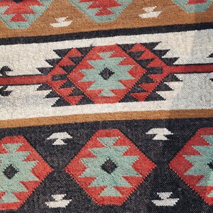 May include: A black, red, and green patterned rug with a geometric design. The rug has a traditional, tribal look.