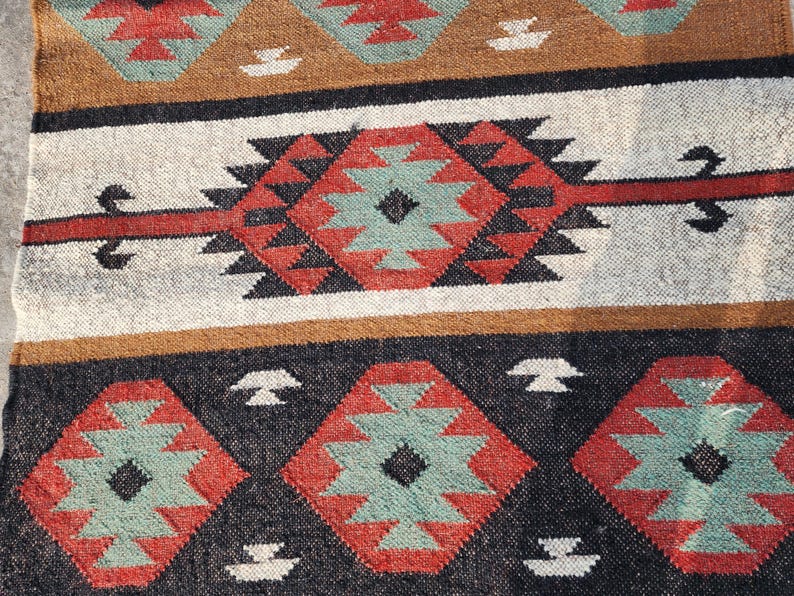 May include: A black, red, and green patterned rug with a geometric design. The rug has a traditional, tribal look.