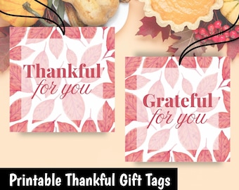 Könnte beinhalten: Zwei quadratische Geschenkanhänger mit den Sätzen "Thankful for you" und "Grateful for you" in einer Schriftart. Die Anhänger haben ein Aquarell-Blattdesign in Rosa- und Rottönen. Das Bild enthält auch ein Banner mit der Aufschrift "Printable Thankful Gift Tags".