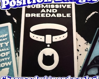 May include: A rectangular black and white badge featuring the text SUBMISSIVE AND BREEDABLE in white lettering above a graphic of a collar with a circular pendant containing a cat silhouette. The badge has a white border and a matte finish.