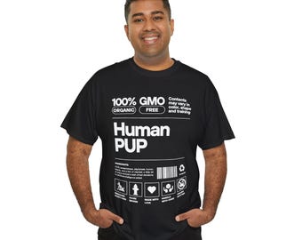 May include: A black short-sleeve t-shirt featuring white text and graphics resembling a product nutrition label. The design includes the words 100% GMO FREE, Human PUP, and a list of ingredients, along with a barcode and five small icons at the bottom.