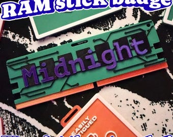 May include: A rectangular RAM stick badge featuring a teal green circuit board design with a black center strip and the word Midnight embossed in purple lettering. The bottom edge is orange, and the badge includes a small hole for attachment.