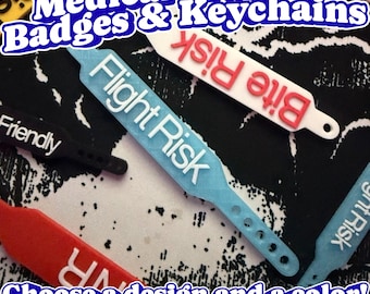 May include: A collection of flexible plastic medical identification straps in various colors including blue, white, red, and black. Each strap features embossed text such as Flight Risk, Bite Risk, and Friendly, with holes at one end for adjustment.