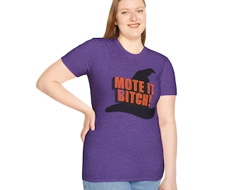 May include: A heather purple short-sleeve t-shirt featuring a black witch hat graphic on the chest. The text MOTE IT BITCH! is printed in orange block letters across the center of the hat graphic. The shirt has a crew neckline and a fitted cut.