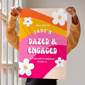 Puede incluir: Un póster rosa, naranja y amarillo con un diseño de margarita blanca. El póster dice "Bienvenido a Jade's Dazed & Engaged Bachelorette Weekend Miami, FL".